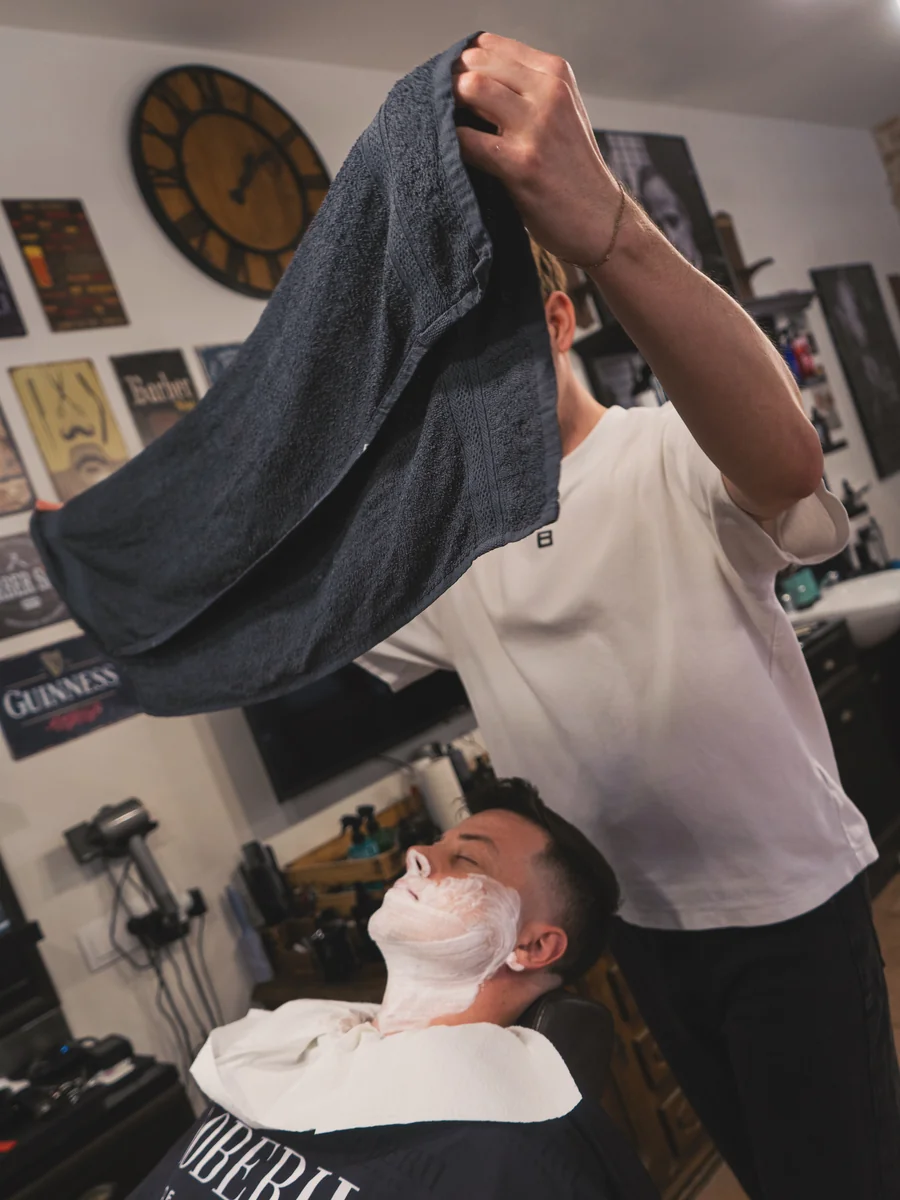 Hot towel holení, barbér připravuje horký ručník – Notorious Barbershop Kyjov